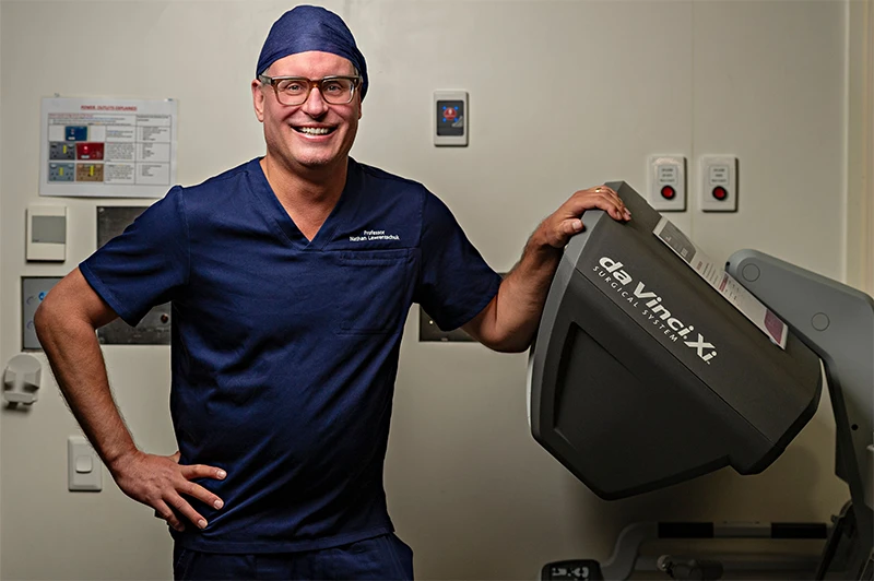 Prof Lawrentschuk standing with the da Vinci robotic system which he uses to perform surgery with greater precision and control